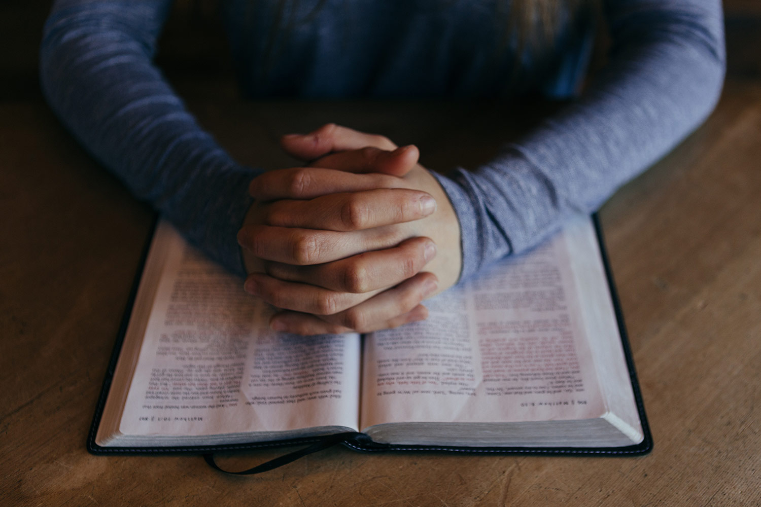 Person in prayer over a Bible